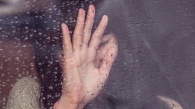 347214 20190529 a sad woman presses her hand against a rainy window