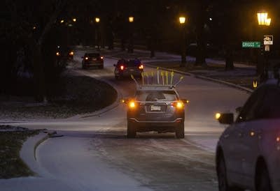 A car with a menorah on its roof goes down a street. 