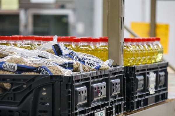 Packages of dry beans and vegetable oil sit in plastic crates.