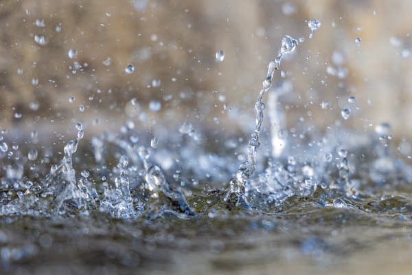 A close up of water splashing into a puddle.