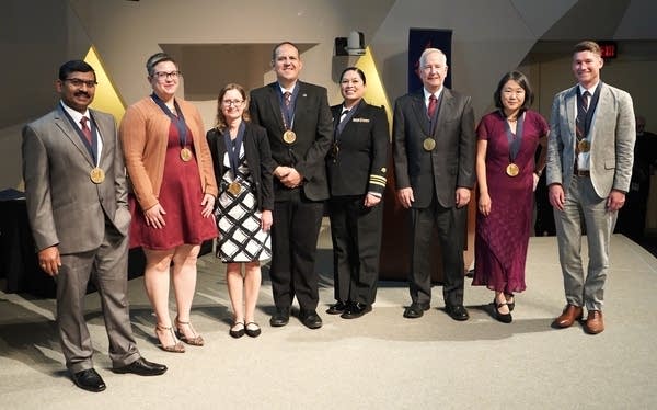 A group of people stand for a picture with awards.