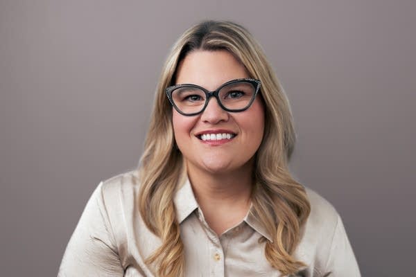 A woman with glasses smiles for a photo