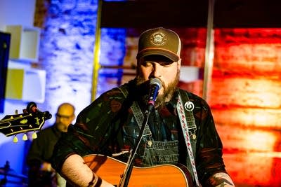 A musician sings and plays guitar onstage
