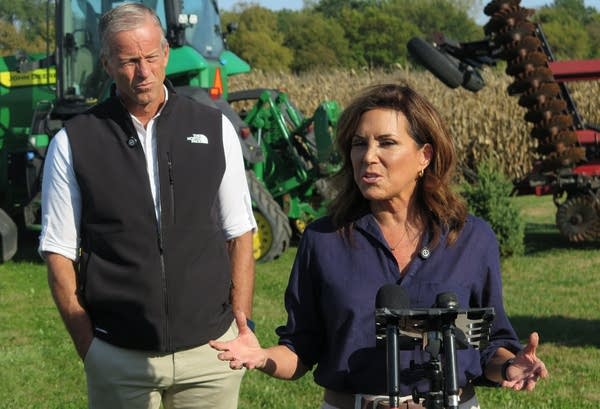Two people speak in a farm field