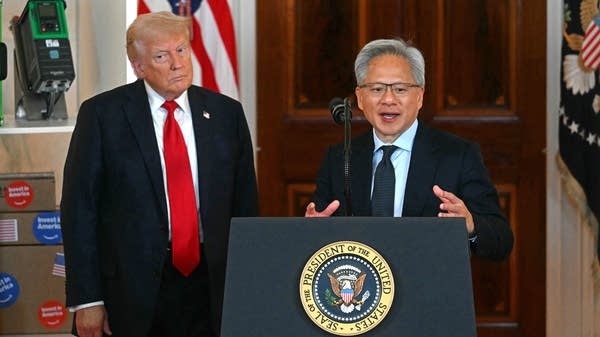 Nvidia CEO Jensen Huang stands at a White House podium. President Donald Trump stands to his right.
