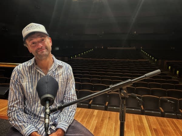 A man posing for a photo on a stage with a microphone