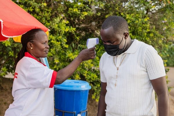 Health worker using a thermometer to screen a man
