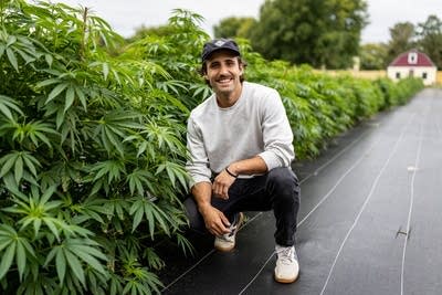 A man poses next to marijuana plants