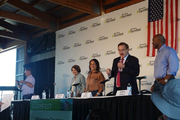 Four people prepare to sit down on a stage.