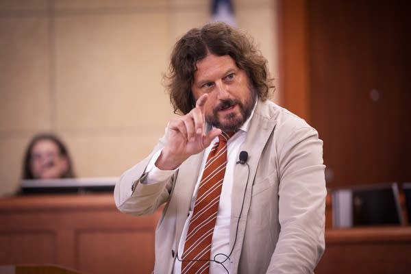 A defense attorney talks at a microphone