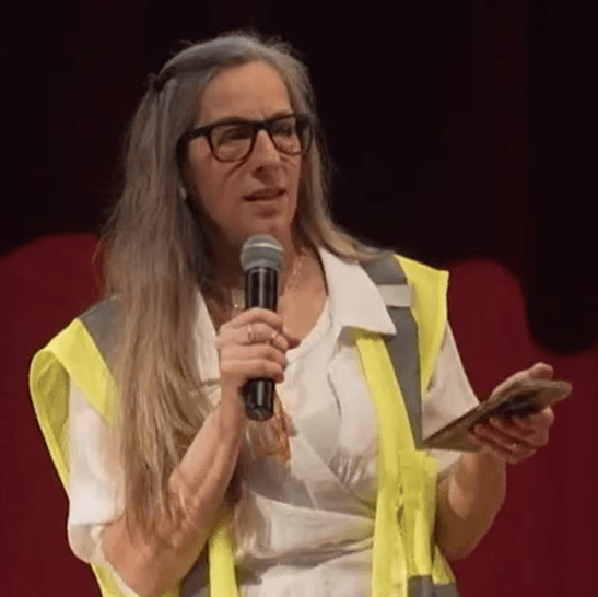 A person in white and yellow shirt holding a mic