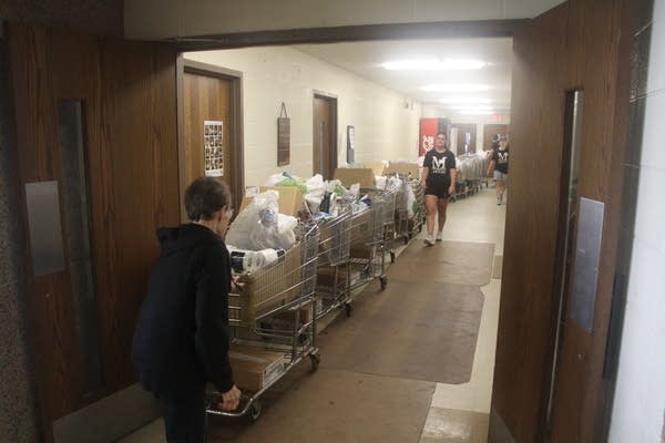 A line of shopping carts filled with bags of food are seen lining a hallway.