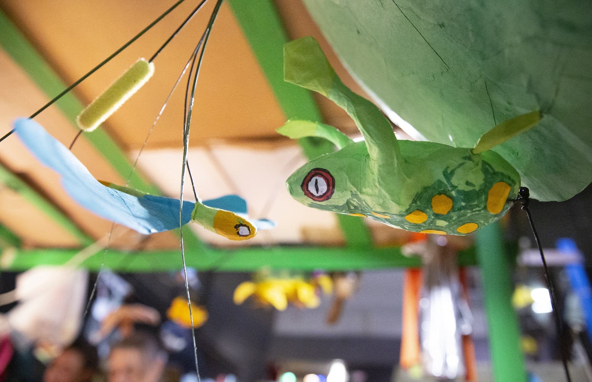 A paper mache frog and dragonfly are hung up to dry.