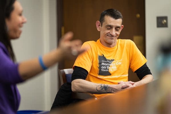 A man wearing an orange shirt smiles