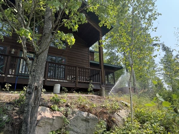 A brown house with a sprinkler running