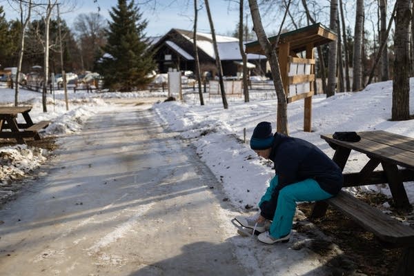 A woman sits at a picnic table and puts on skates
