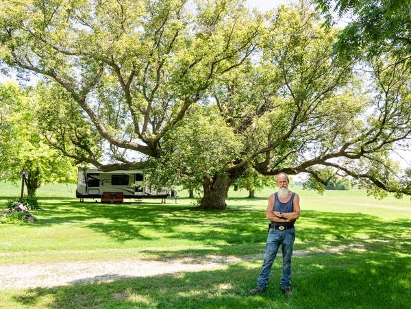 a man stands near a large tree