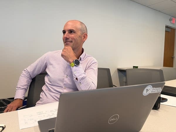 a man sits behind a silver laptop