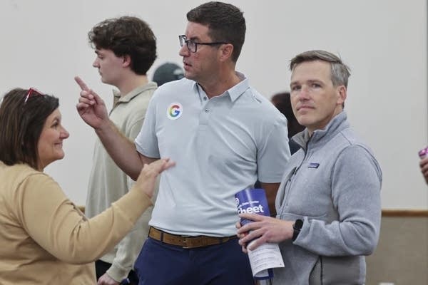 Three people talk during a public meeting.