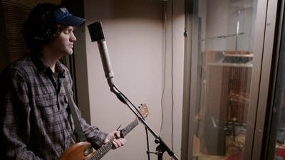 A man plays guitar in a recording studio