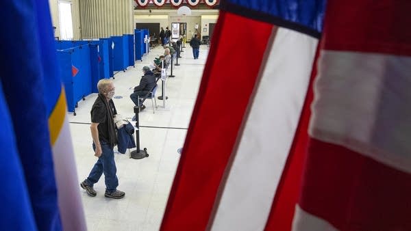 People sit in chairs behind a US flag.