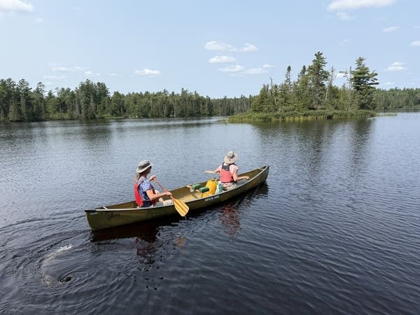 Two people paddle a canoe on a lake.