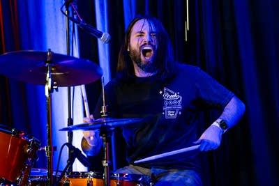 Drummer performing on stage with mouth open