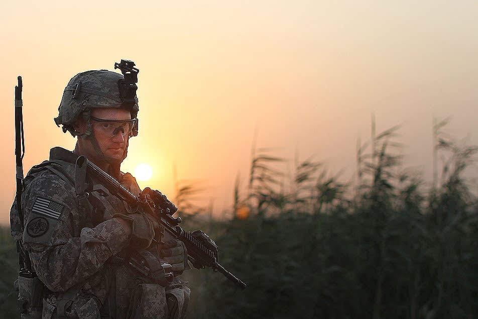 The sun sets behind a U.S. soldier in Iraq