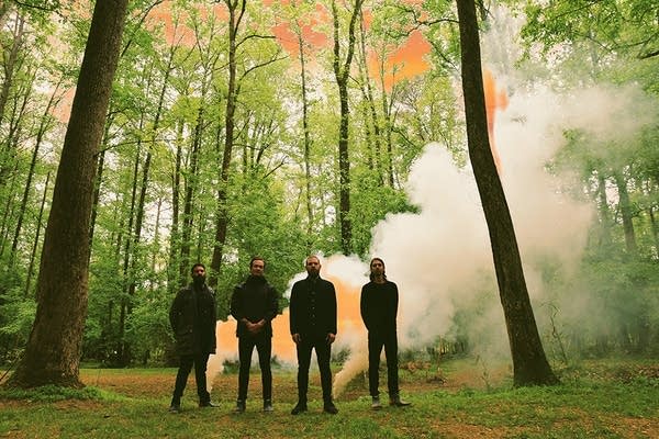 Four men standing by two plumes of smoke in the Georgia woods