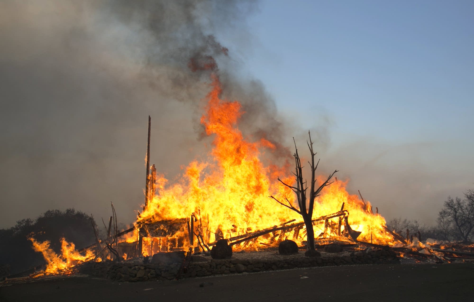 Flames from a wildfire consume a home east of Napa, Calif.