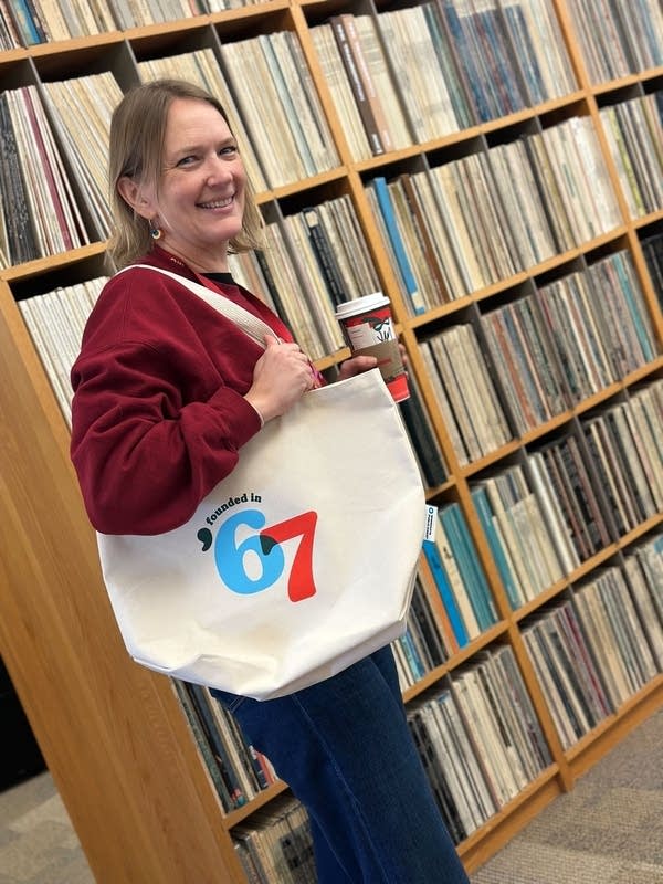 MPR staff member holds up a 67 tote bag