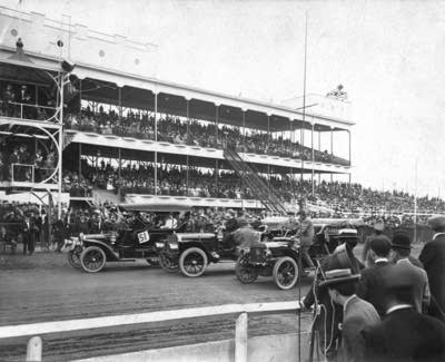 A black and white photo of an auto race at the Grandstand.