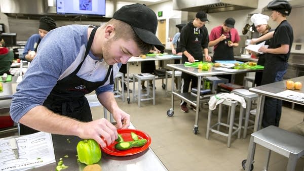 Mac Somerville finishes on his cucumber shark creation in culinary class.