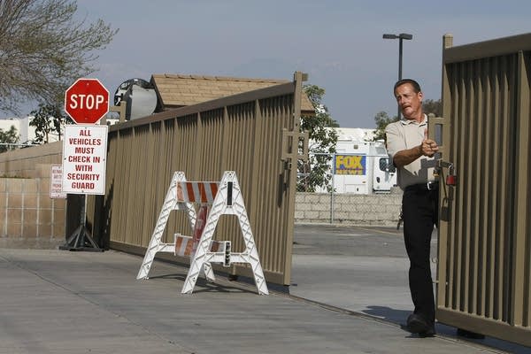 A security guard pulls the gate shut to