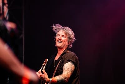 A musician sings and plays guitar on a large outdoor stage