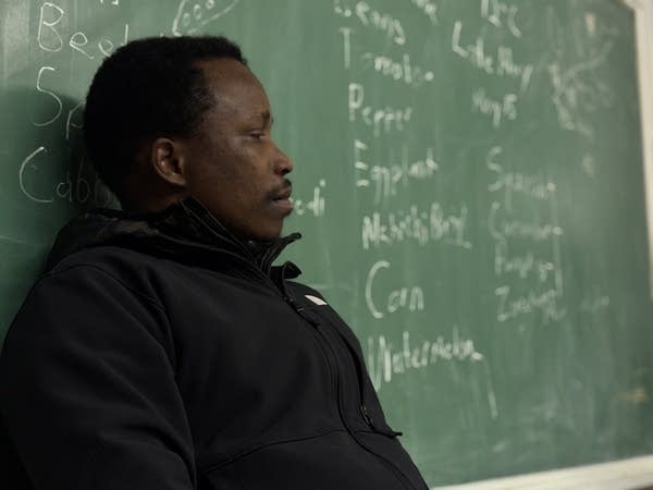 A person leans against a blackboard