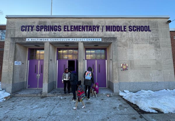 The entrance to a school building, with doors and lettering in purple.