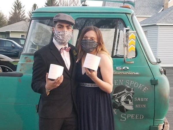 two teenagers wearing masks stand in front of a vintage truck