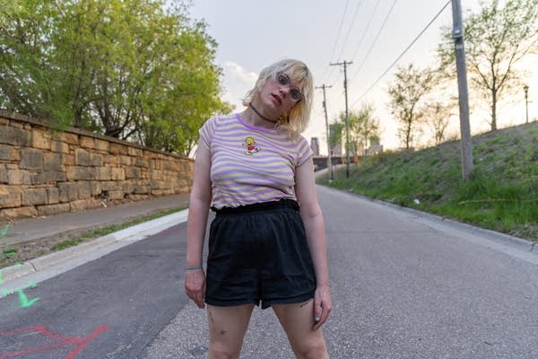 Woman in street with brick wall and grass on either side