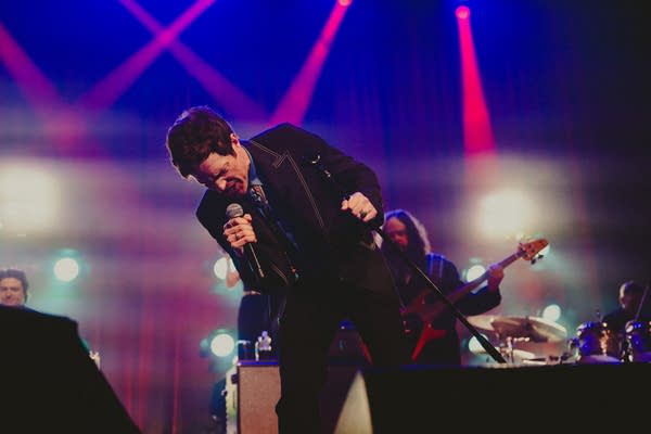 A musician sings onstage in a large music venue
