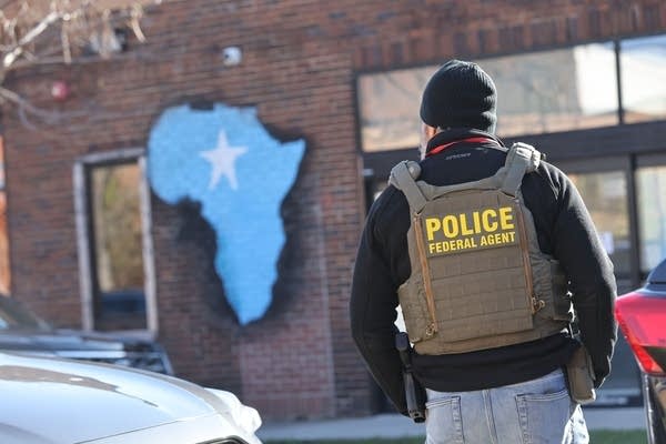 A federal police officer stands with his back to the camera.