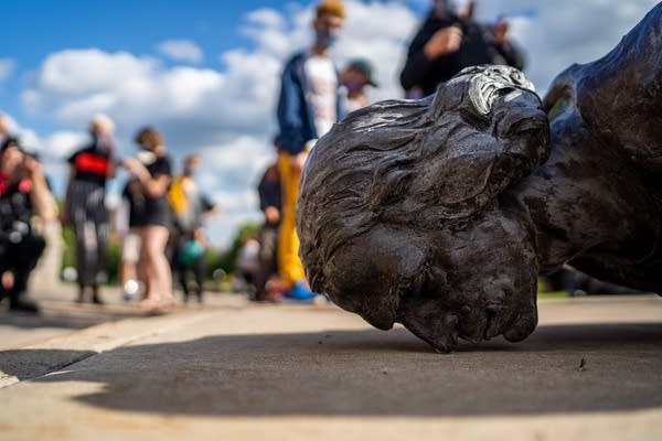 A statue lies face down on the ground.