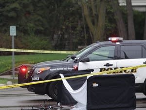 Police examine the scene of a crash between a school bus and a bicyclist.
