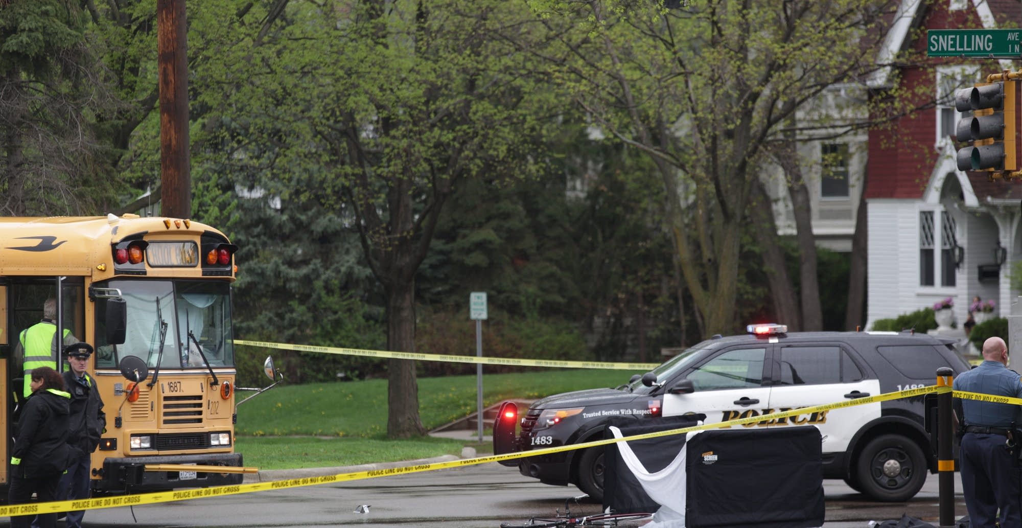 Police examine the scene of a crash between a school bus and a bicyclist.