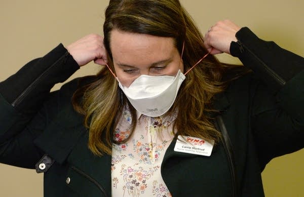 A woman places a mask over her face. 