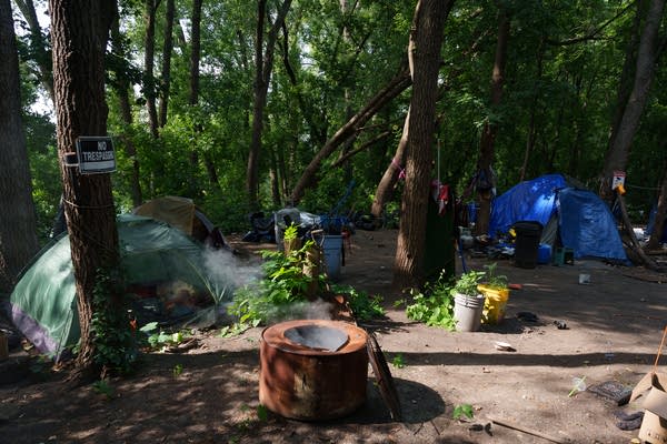 An encampment sits in a clearing in the woods.