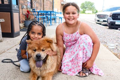 two children sit with dog outside for photo 