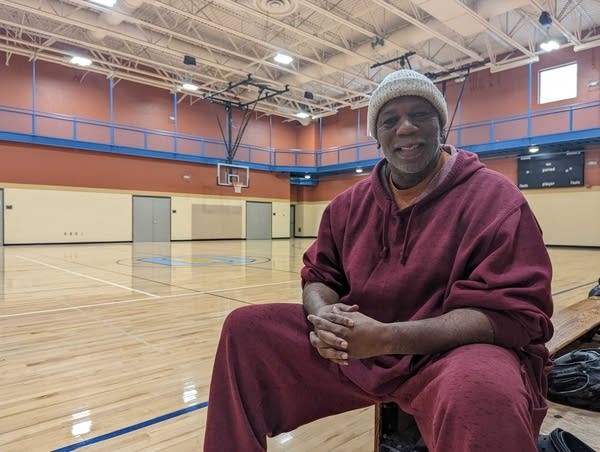 A man sits on a bench inside the gymnasium.