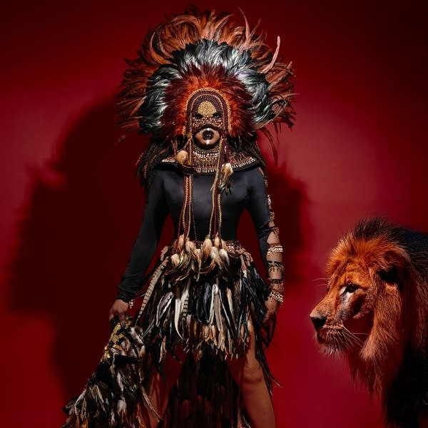 A drag performer poses next to a lion.