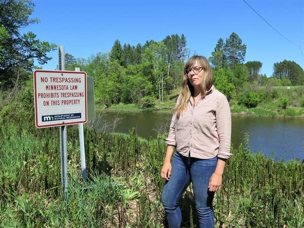 A woman stands next to a river.